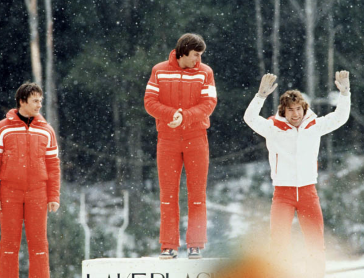 An Olympic athlete raises his hands in the air in celebration on a medal podium at the 1980 Olympics in Lake Placid.